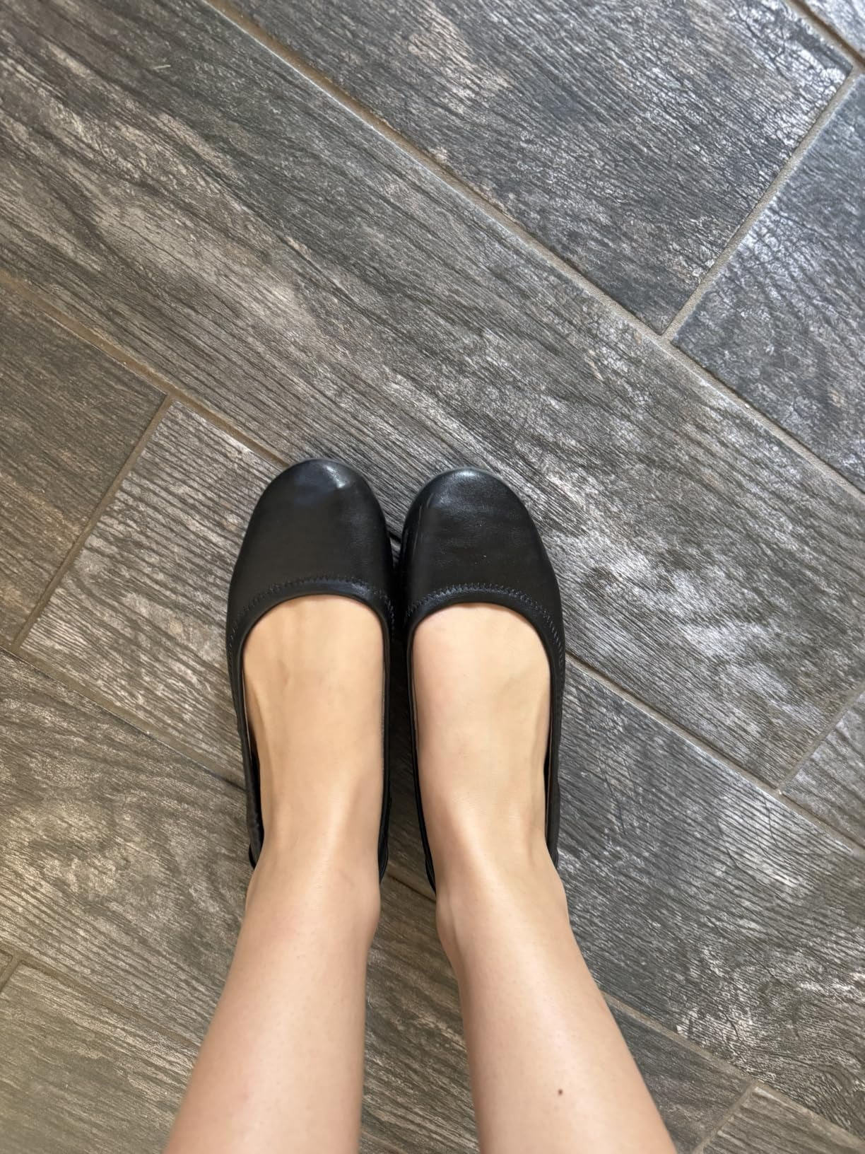 Pair of elemental  ballet flats worn connected  a tiled floor. Perfect for mundane  comfortableness  and style