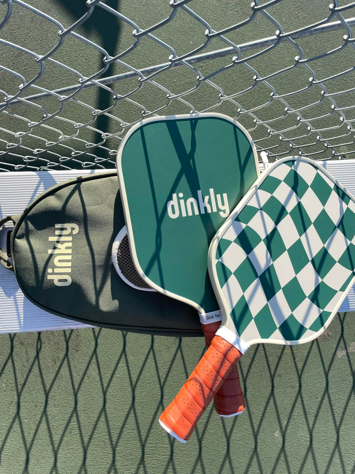 green paddles with a checkered plan  and container  connected  a seat  with the pickleball nett  and shadiness   disposable   successful  the background