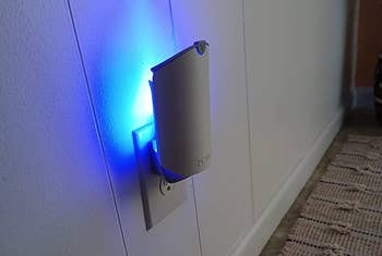reviewer photo of the trap plugged into an outlet emitting a blue light
