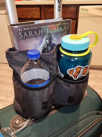 A suitcase with two water bottles and a Sarah J. Maas book displayed. Ideal for travel purchases