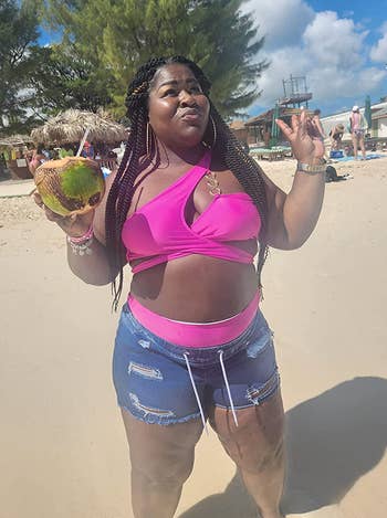 A reviewer wearing jean shorts with the pink set on the beach