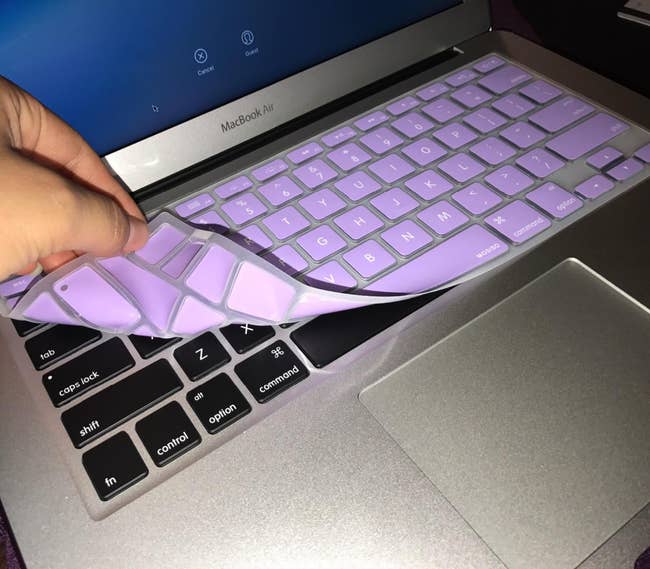 Person peeling off a purple keyboard cover from a laptop