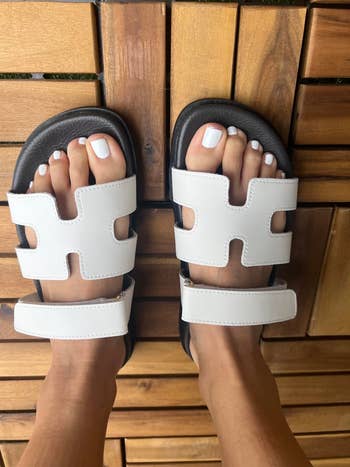 Person wearing stylish achromatic  sandals with a double-strap design, showing a minimalist and comfy  look   for casual outings