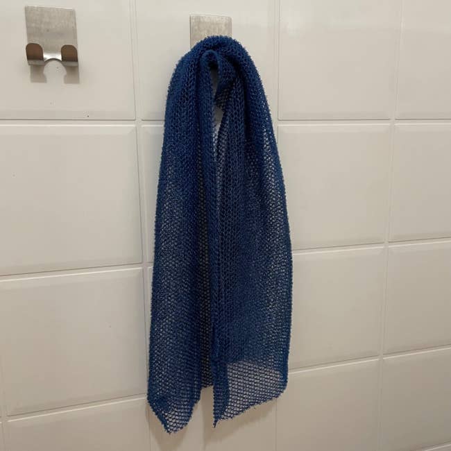 Blue African Net Sponge hanging connected a hook against a tiled wall