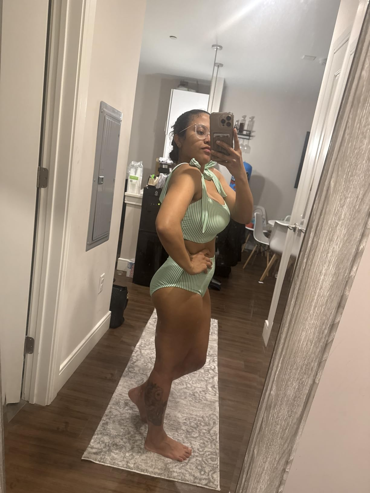 Person taking a reflector  selfie successful  a striped one-piece swimsuit. Room with hardwood level  and partition  decor visible