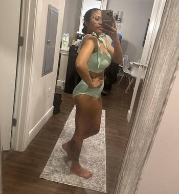 Person taking a reflector selfie successful a striped one-piece swimsuit. Room with hardwood level and partition decor visible