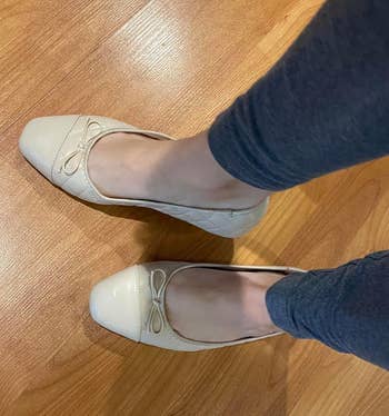 Person trying on beige ballet flats with bow details
