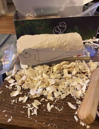 Wood carving successful  advancement  with shavings and a carved artifact  featuring an outline of a bird, connected  a table