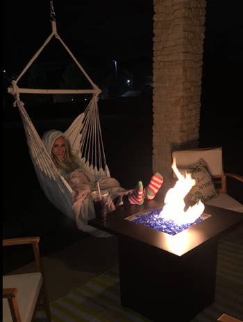 reviewer in hammock chair hanging from deck beside fire
