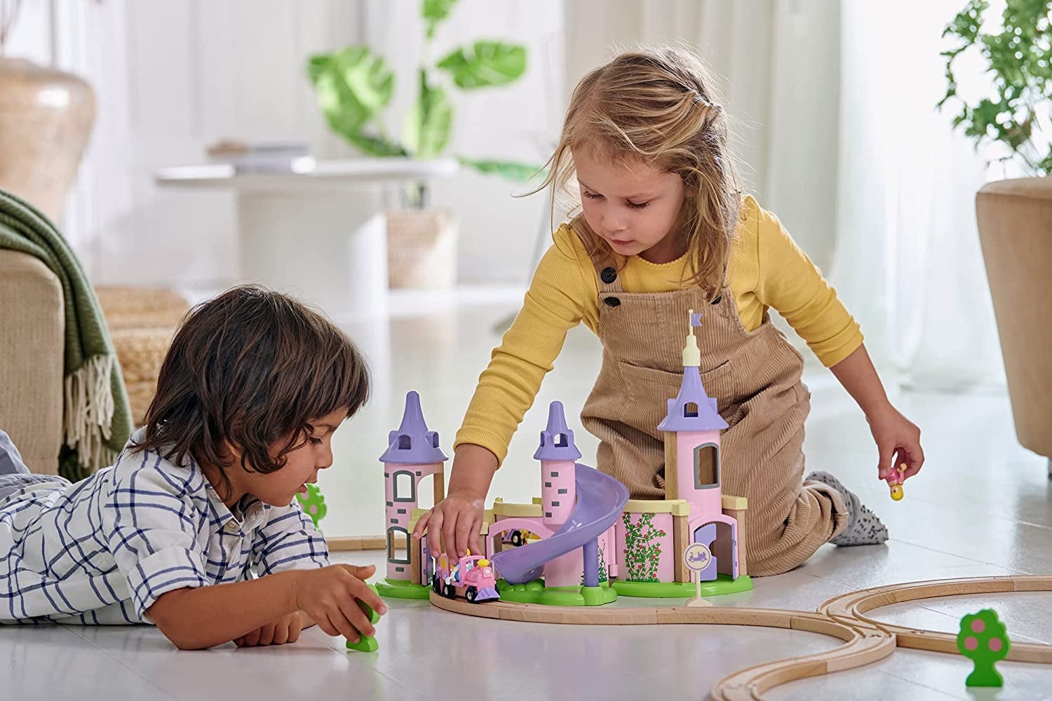 two children playing with a castle and train set