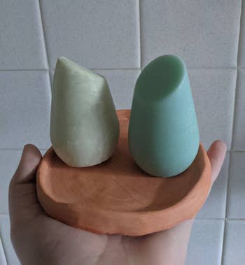 Reviewer holding green shampoo and conditioner shampoo bars on a brown tray