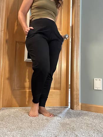 Person in casual black pants and a top, viewed from the side. Focus on clothing fit for a shopping article