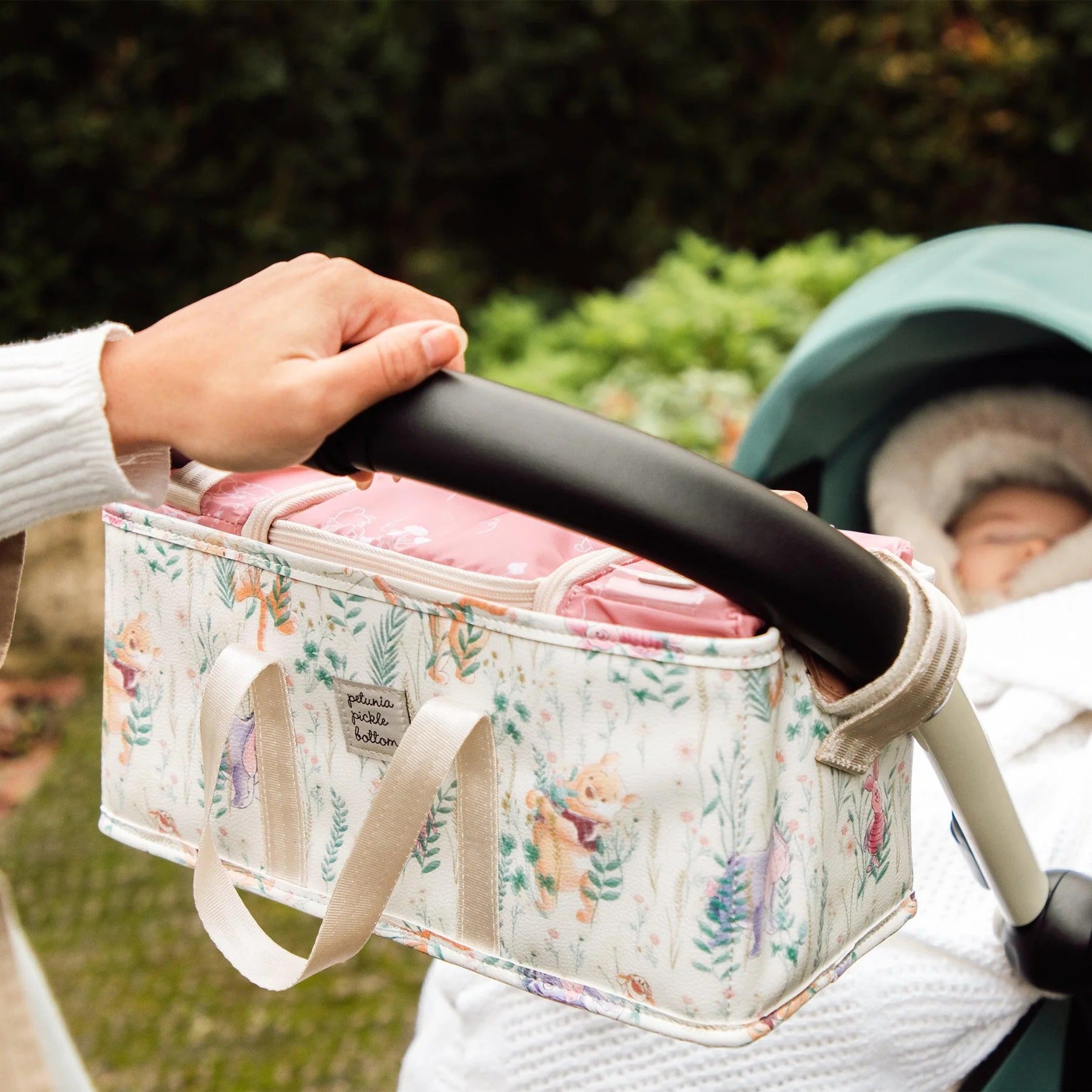 an ivory stroller caddy with a print of winnie the pooh and various plants on it