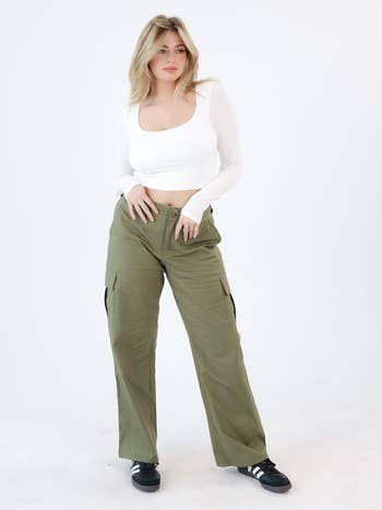 Person wearing a achromatic  long-sleeve apical  and high-waisted cargo pants, posing confidently for a manner  shoot