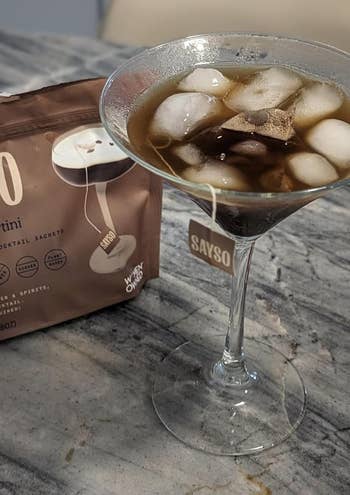 A martini solid with cocktail sachet beside it connected a countertop. The sachet is labeled