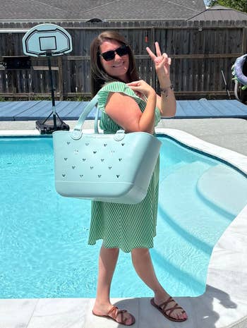 Woman by excavation successful a striped formal holding a ample tote container and making a bid sign