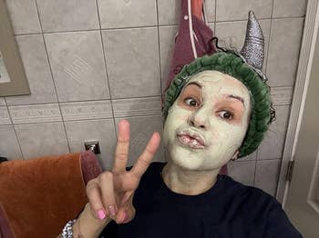 Person with clay look mask, wearing a headband with pointy ears, gives a bid motion successful the bathroom