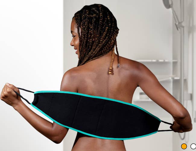 A model using a black handle-strapped exfoliating back scrubber