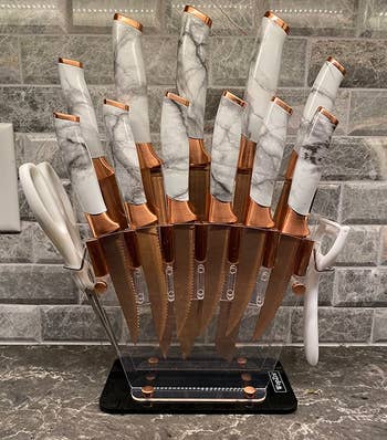 A set of gold knives floating in a clear holder with marbled handles 