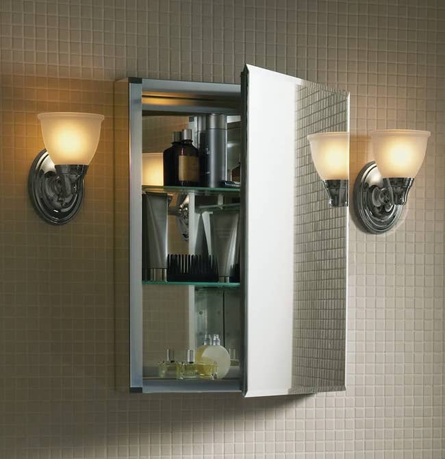 the open mirrored medicine cabinet with toiletries inside of it