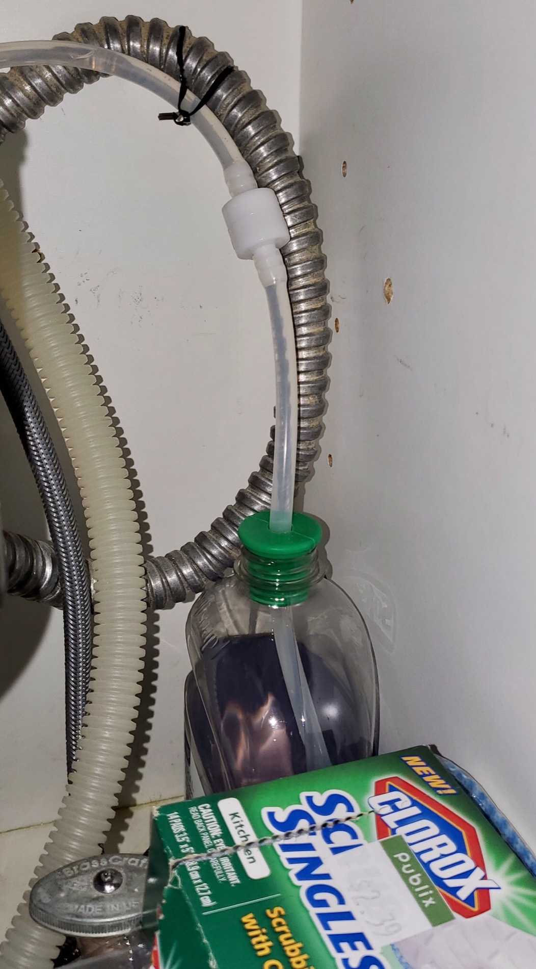 pengulas menunjukkan botol sabun di bawah wastafel mereka dengan tabung di dalamnya yang mengarah ke dispenser di atas