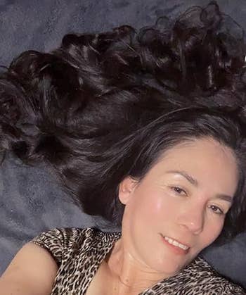 reviewer lying connected  a textured aboveground  with long, wavy hairsbreadth  dispersed  out, wearing a leopard people     top