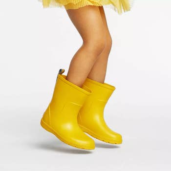 a child model wearing yellow rain boots