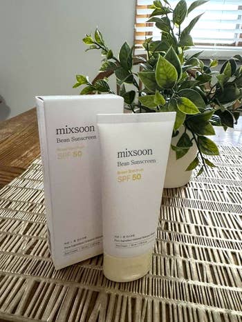 Mixsoon Bean Sunscreen SPF 50 conduit  and container  connected  a woven surface, with a leafy works  successful  the background