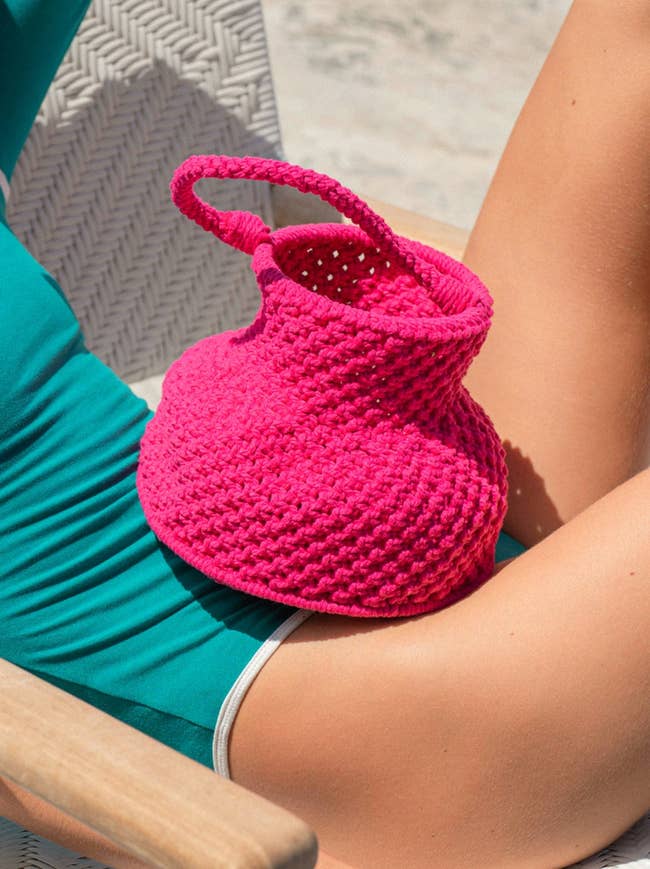 model with hot pink woven bag on their lap