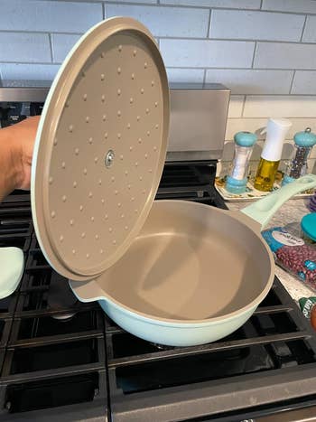 Reviewer holding the lid above a non-stick pan on stove