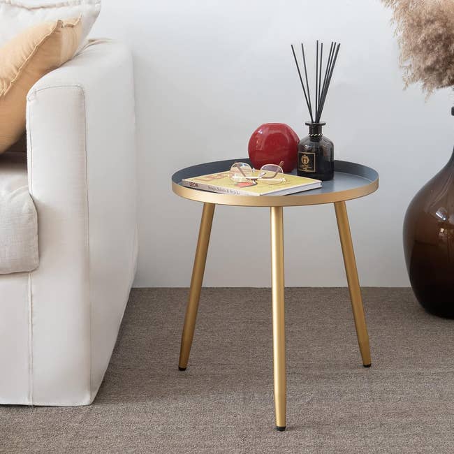 Small circular side table with accessories near a sofa, illustrating a home decor setup for shopping inspiration