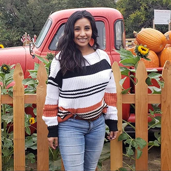 reviewer wearing the white, black, and orange striped sweater with jeans