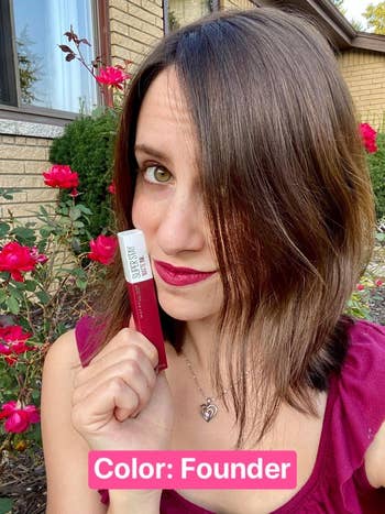 Person outdoors holding a lipstick labeled