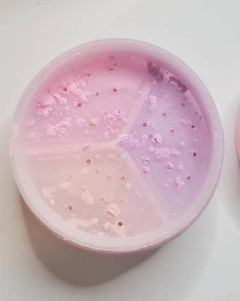 Open makeup container with pastel powder inside, divided into sections, used for setting or finishing