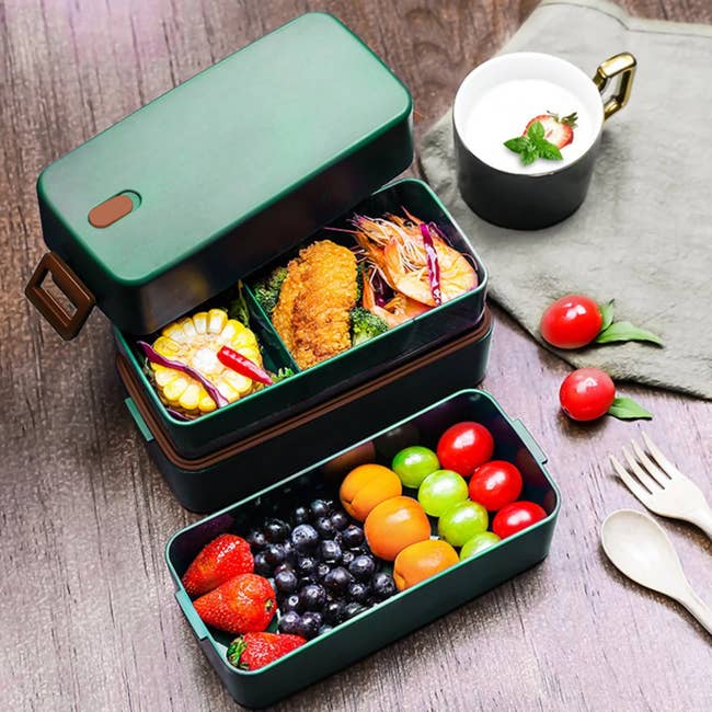 the two open layers of a green bento box full of food