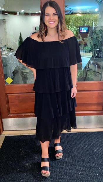a reviewer in a tiered, pleated dress with off the shoulder sleeves