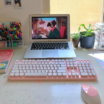 reviewer's pink keyboard and mouse set with a laptop on a desk