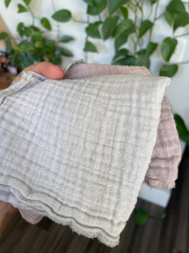 A manus  holds textured cloths successful  beforehand   of a leafy works  background