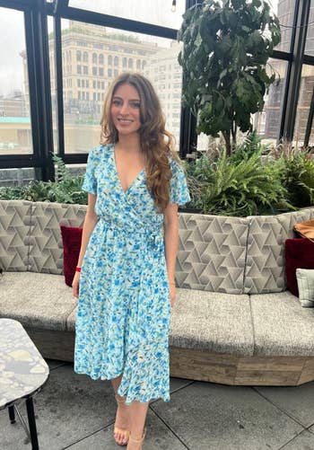 reviewer in a blue floral dress standing in a greenhouse-style room