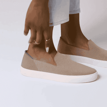 model using hand to show the flexible brown slip-on 