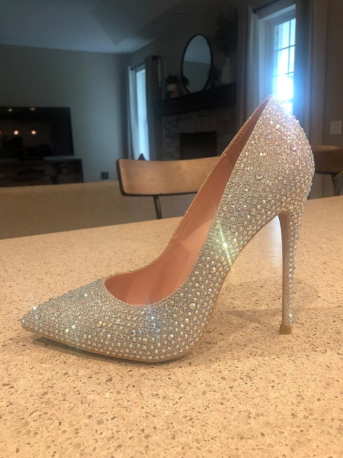 Sparkling high-heeled shoe covered in small rhinestones, displayed on a countertop in a modern living space