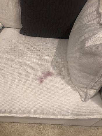 reviewer's white couch with a red wine stain on it