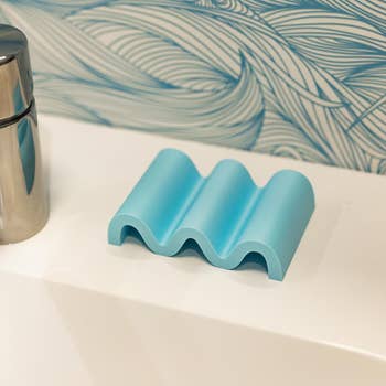 Wave-shaped bathtub headrest connected  a ledge adjacent   metallic  container