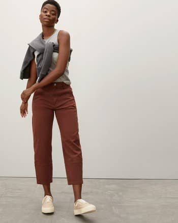 Model in cropped brown trousers with white sneakers