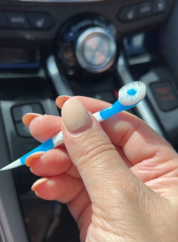 reviewer holding the blue mini toothbrush