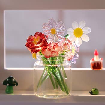 Glass angiosperm bouquet successful a jar with decorative miniatures, including a mushroom and ladybug, placed connected a shelf