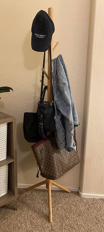 Reviewer image of light brown coat rack with coats, hats, and purses