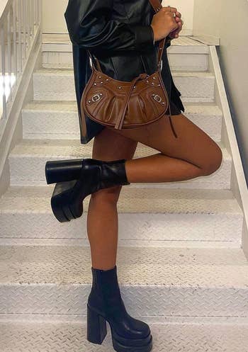 model wearing the black boots with a leather jacket