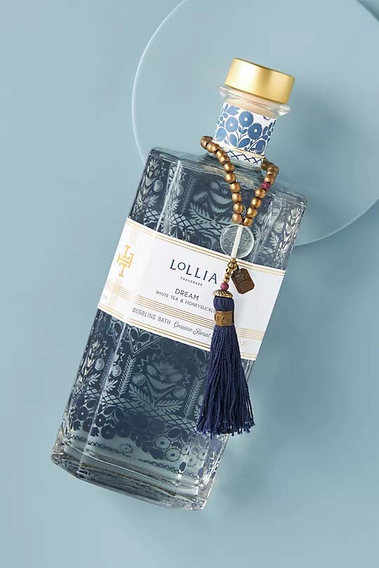 a blue bottle of bubble bath with a decorative tassel on it
