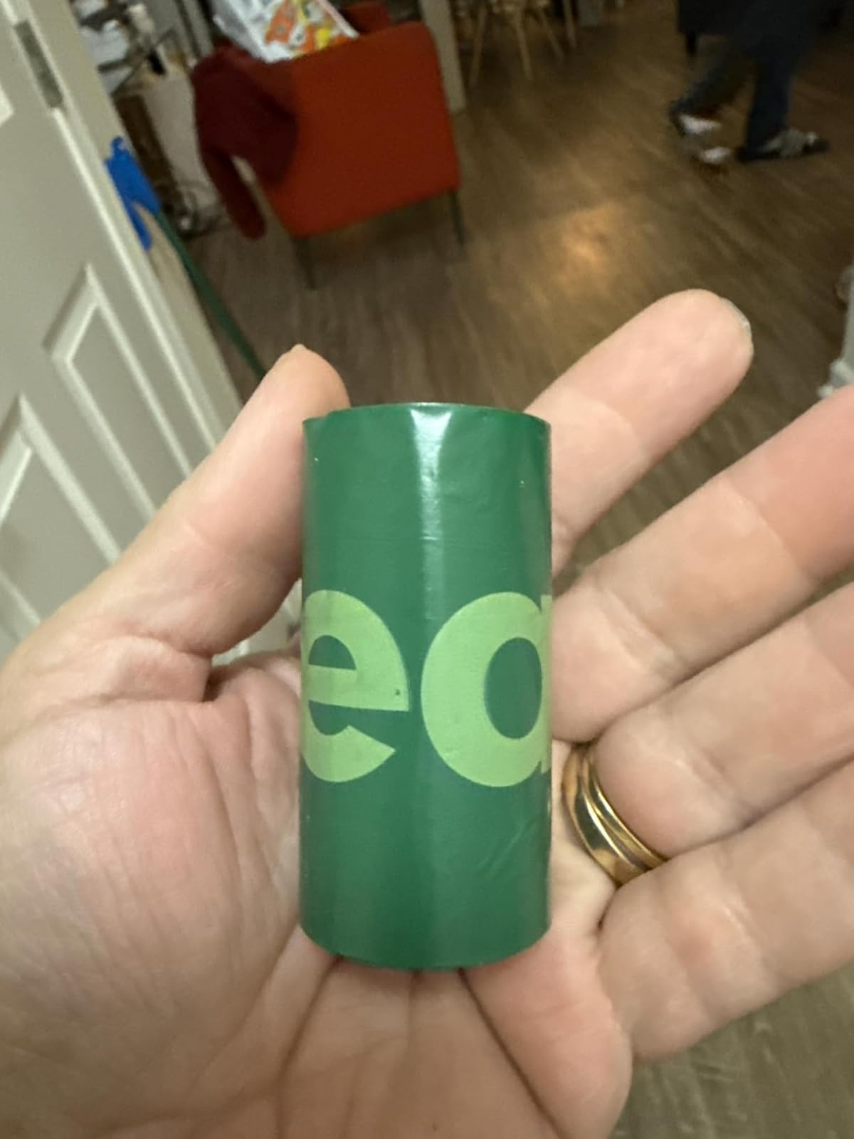 Hand holding a small, greenish  cylindrical object, perchance  packaging oregon  a container